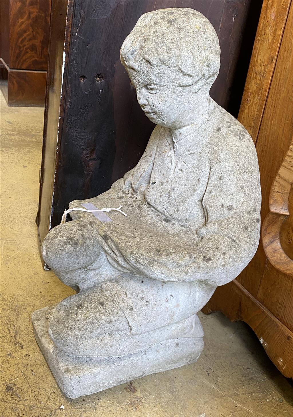 A reconstituted stone garden ornament of a boy reading, height 50cm